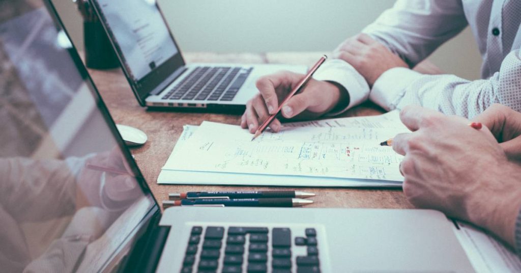 Photo of a person holding a pencil next to a computer by Helloquence on Unsplash